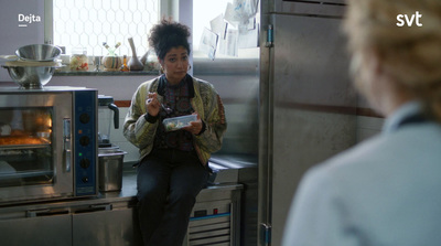 a woman is sitting in front of a microwave in a kitchen