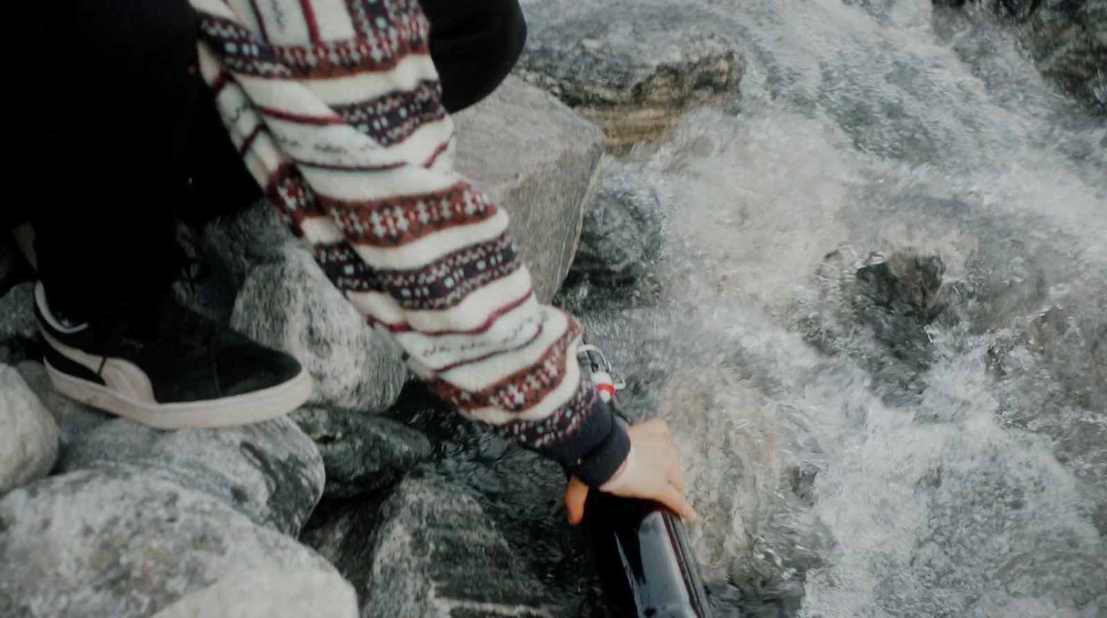 a person sitting on rocks next to a river