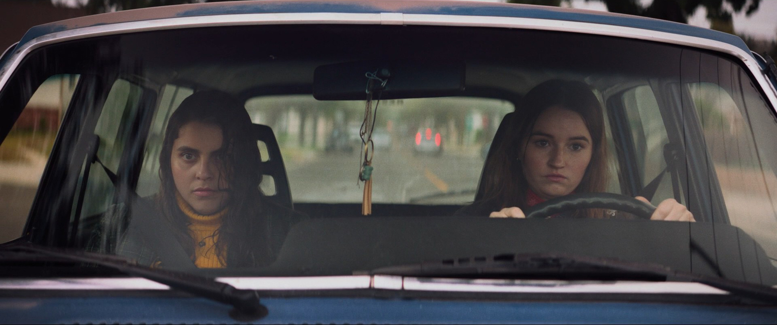 two women in a blue car driving down the road