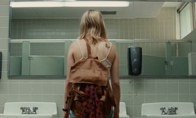 a woman standing in a bathroom with a backpack