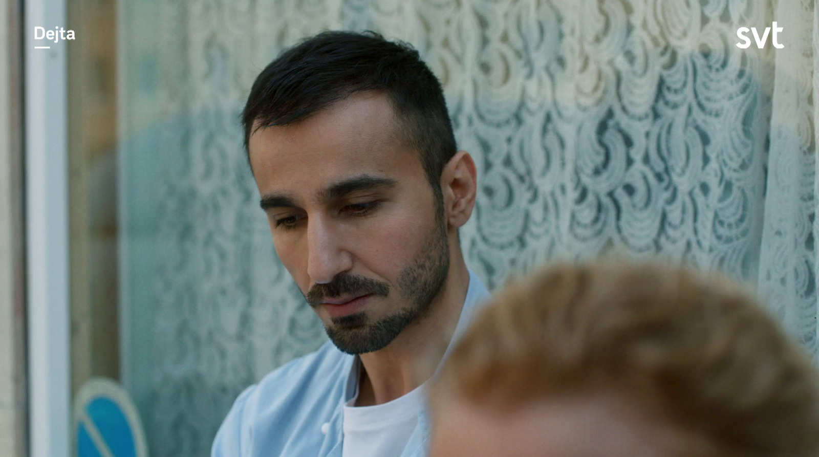 a man in a blue shirt is looking at a window