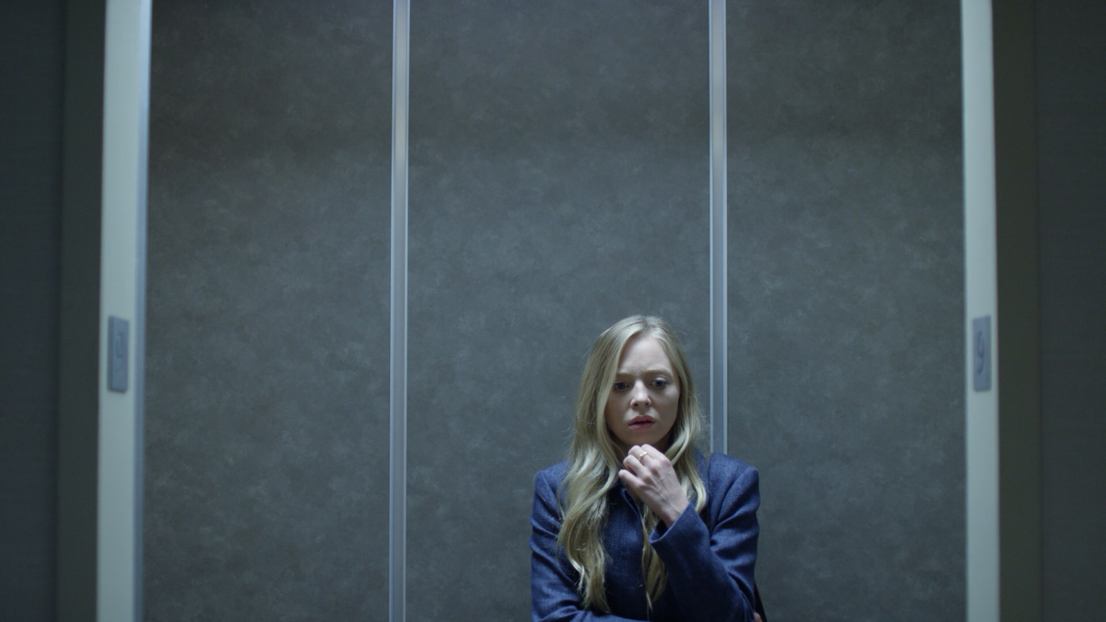 a woman in a suit sitting in a room