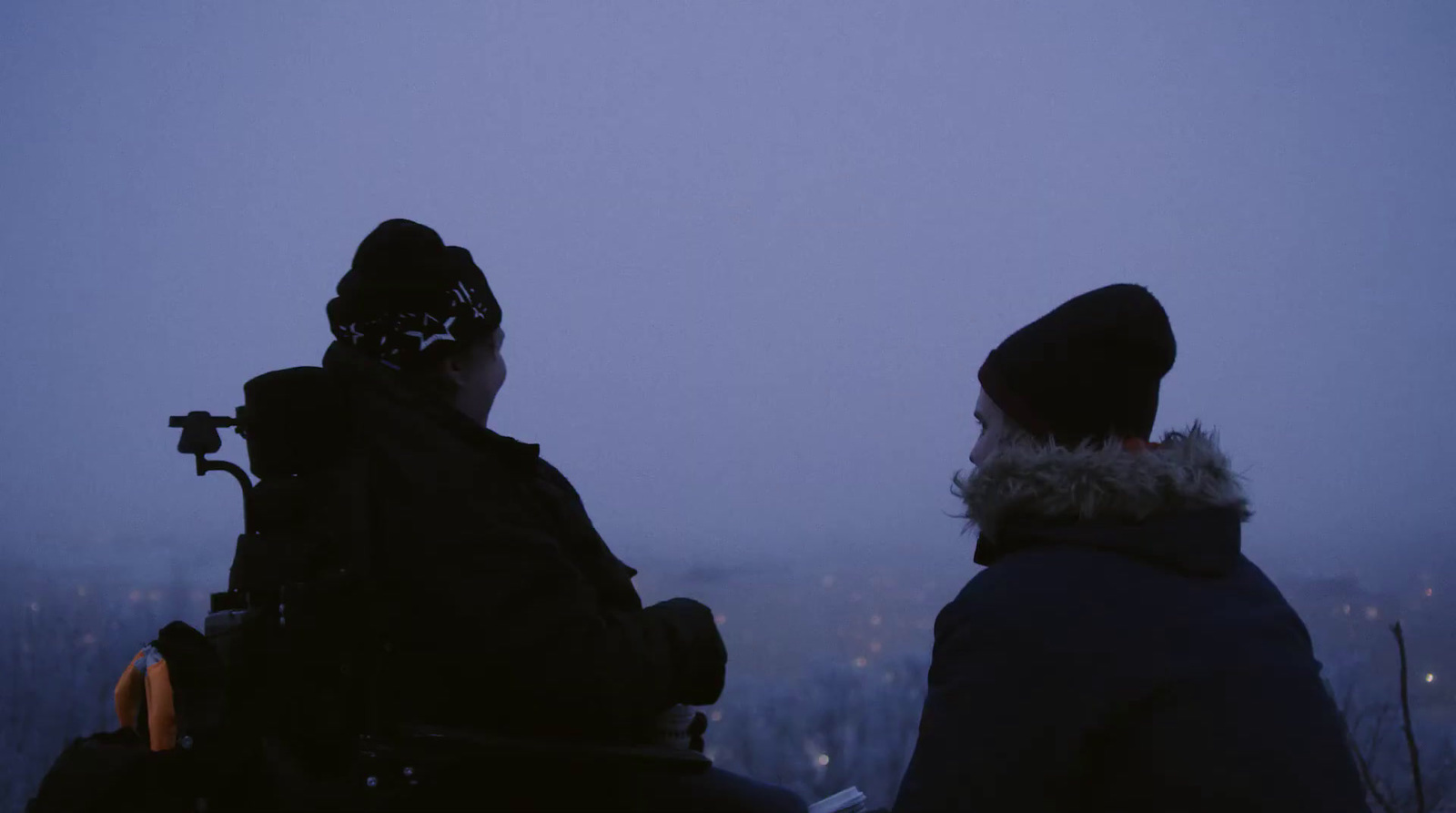 two people sitting in a wheelchair looking at the sky