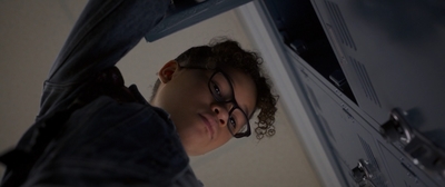 a boy in glasses is hanging from a locker