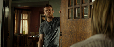 a man standing in front of a door looking at a woman