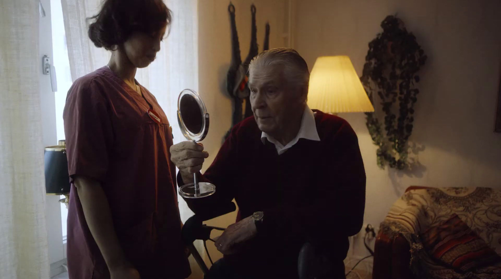 an old man is holding a mirror in front of a woman