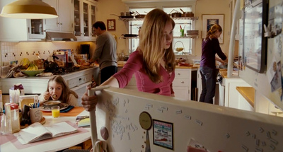 a group of people in a kitchen with a refrigerator