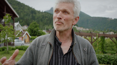 a man with white hair standing in front of a mountain