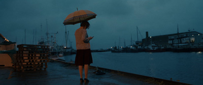 a woman standing on a dock holding an umbrella