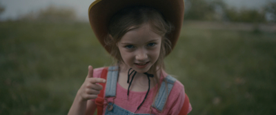 a little girl wearing a cowboy hat and giving a thumbs up