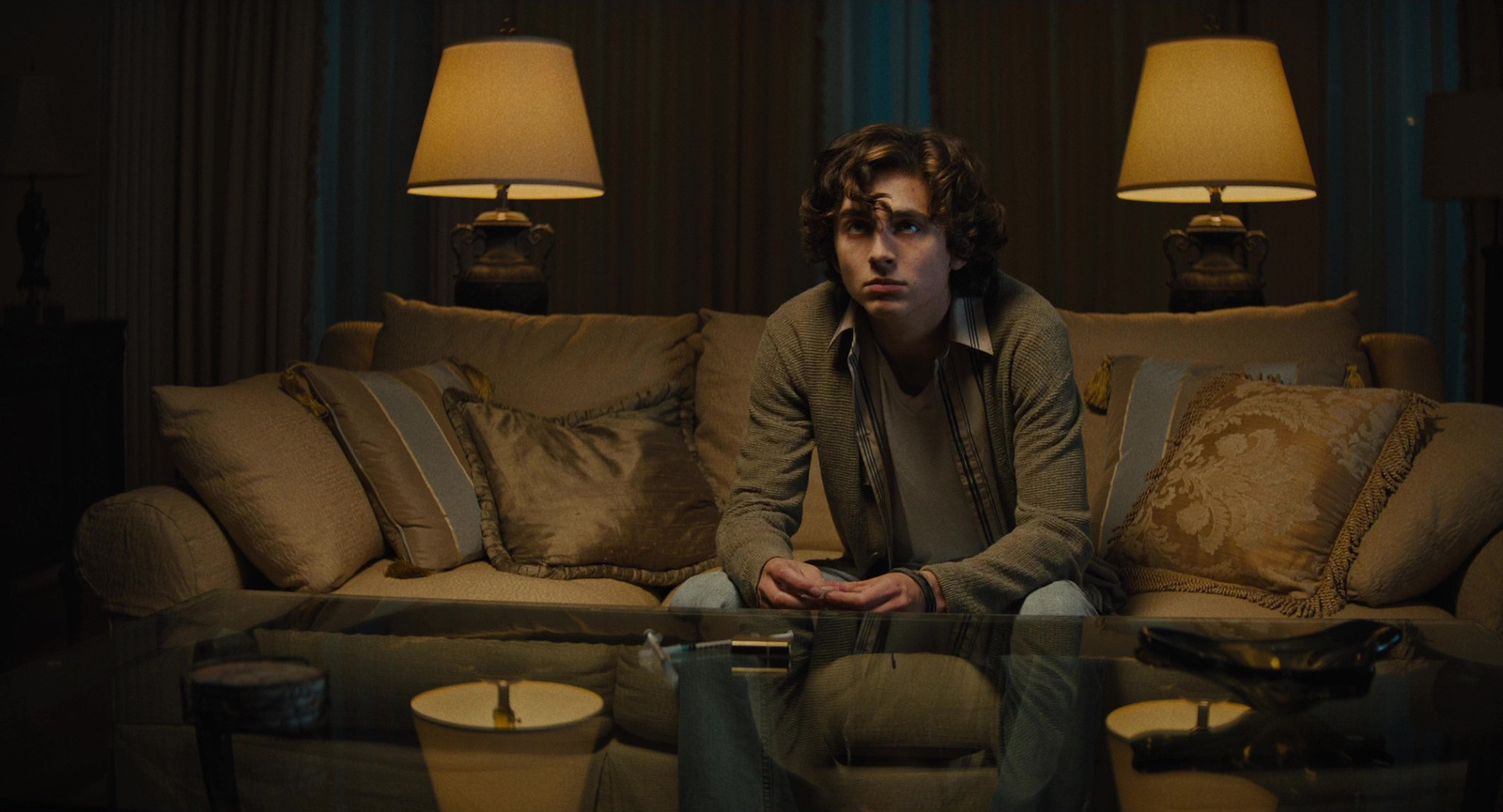 a young man sitting on a couch in a dark room