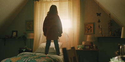 a girl standing on top of a bed in an attic