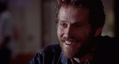 a man with a beard is smiling in a movie