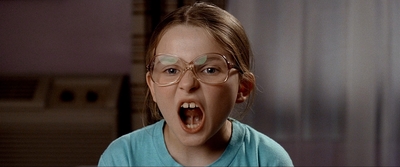 a young girl with glasses is making a funny face