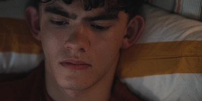 a young man laying in bed with his eyes closed