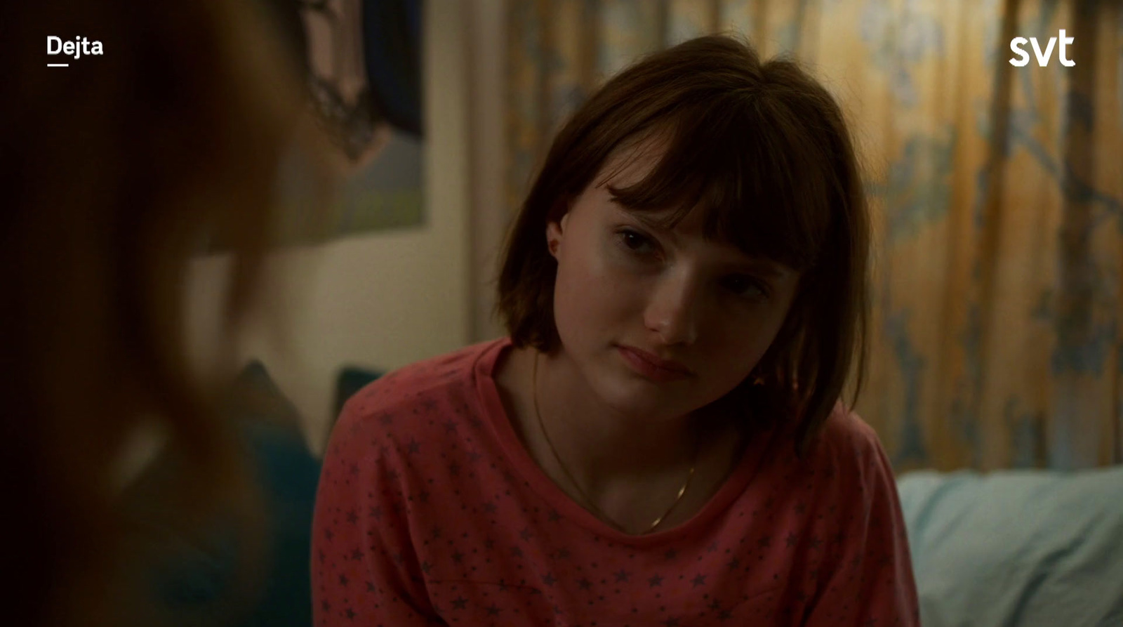 a young girl in a pink shirt is sitting in a bed