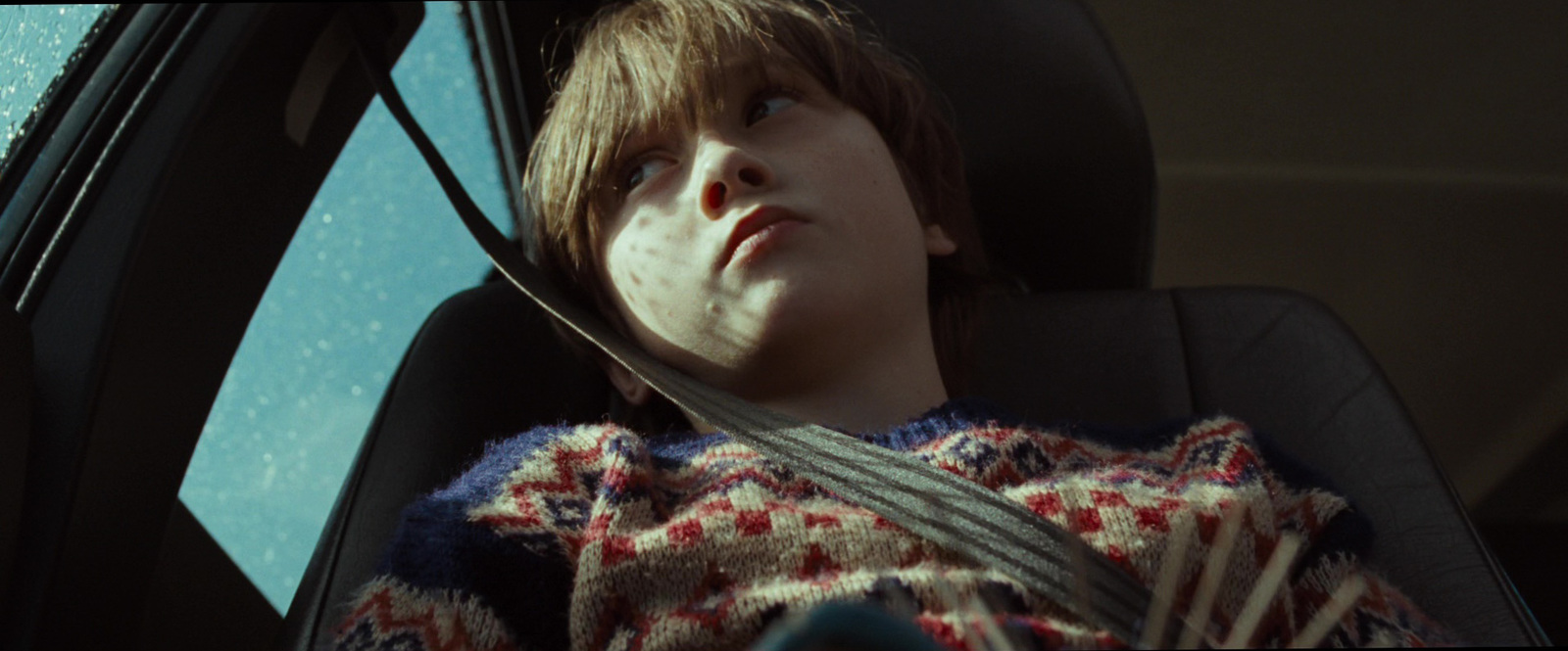 a young boy sitting in the back seat of a car