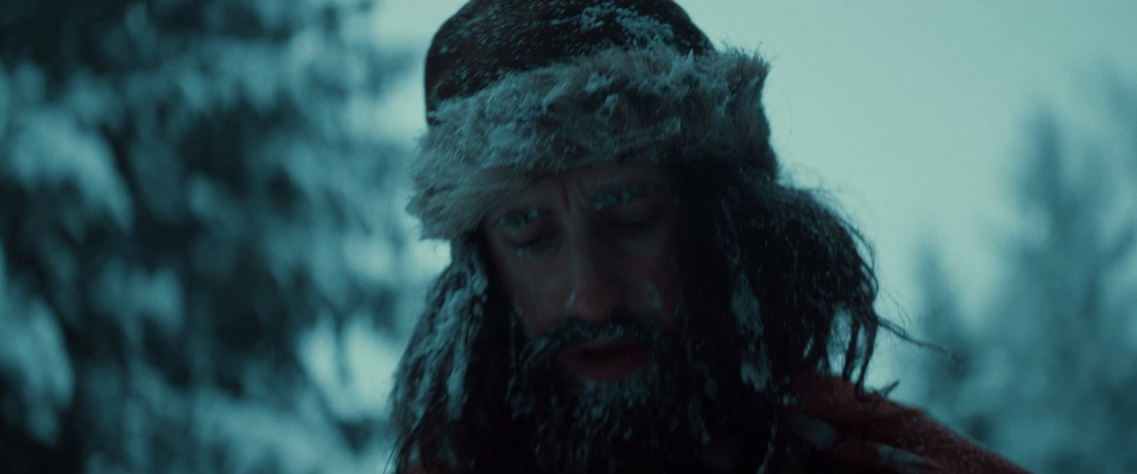 a bearded man in a hat is standing in the snow