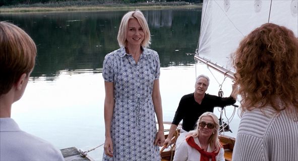 a group of people standing on a boat with a boat in the background