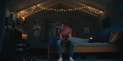 a man sitting on top of a bed in a room with string lights