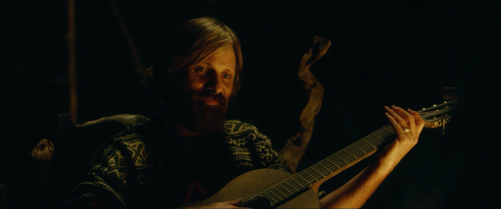 a man with a beard playing an acoustic guitar