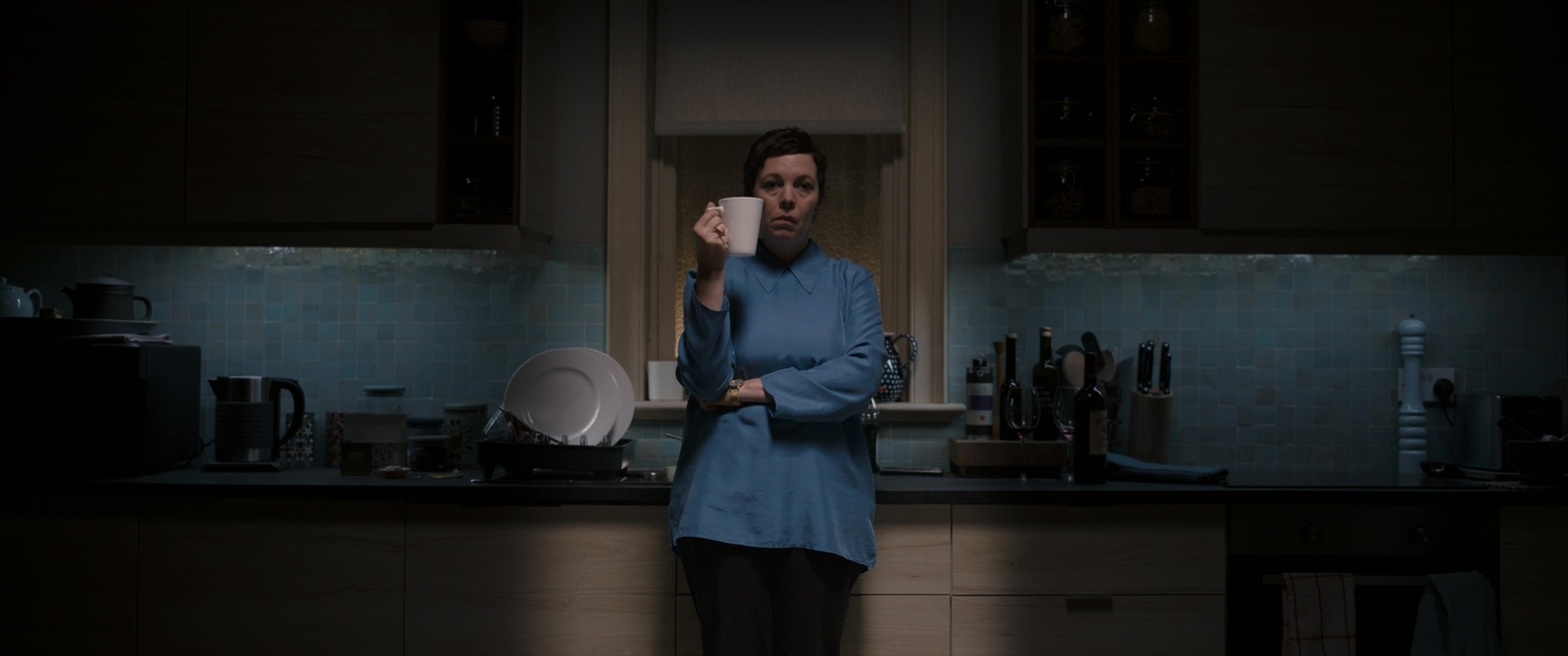 a woman standing in a kitchen holding a cup of coffee