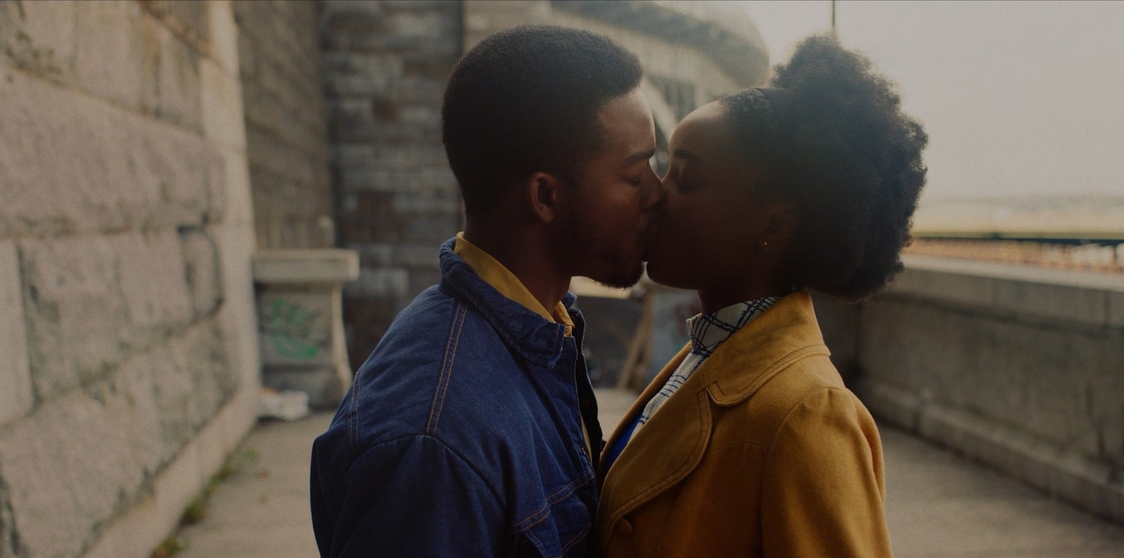 a man and woman kissing in front of a wall