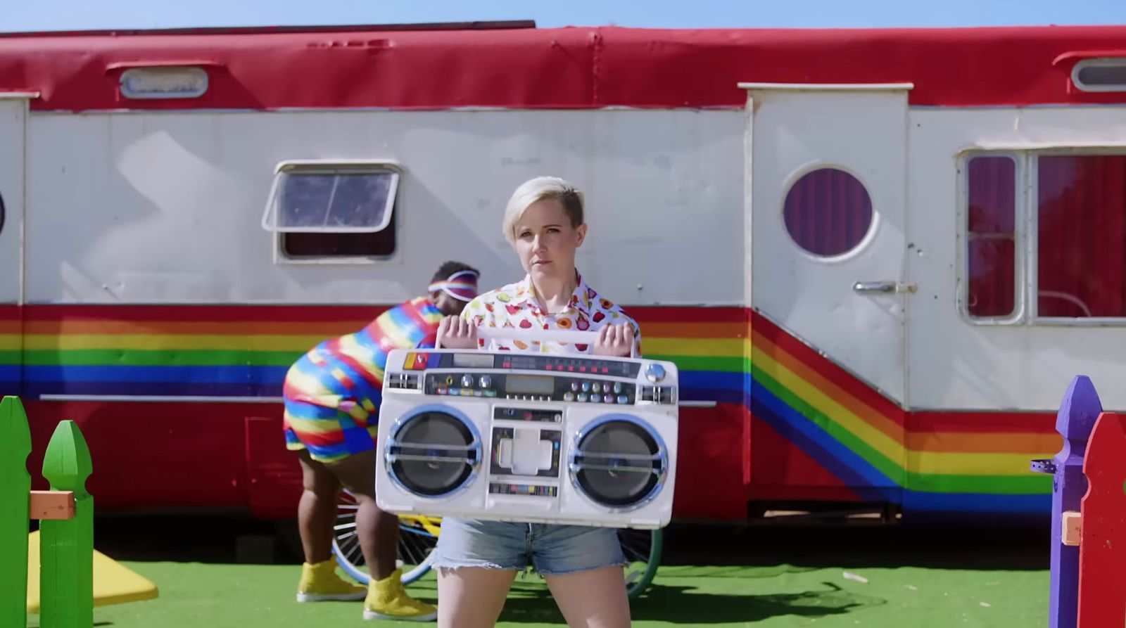 a woman holding a boombox in front of a trailer