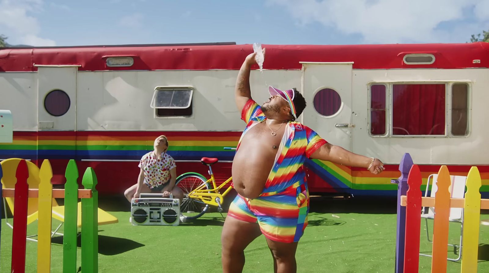 a man in a rainbow striped bathing suit standing in front of a train