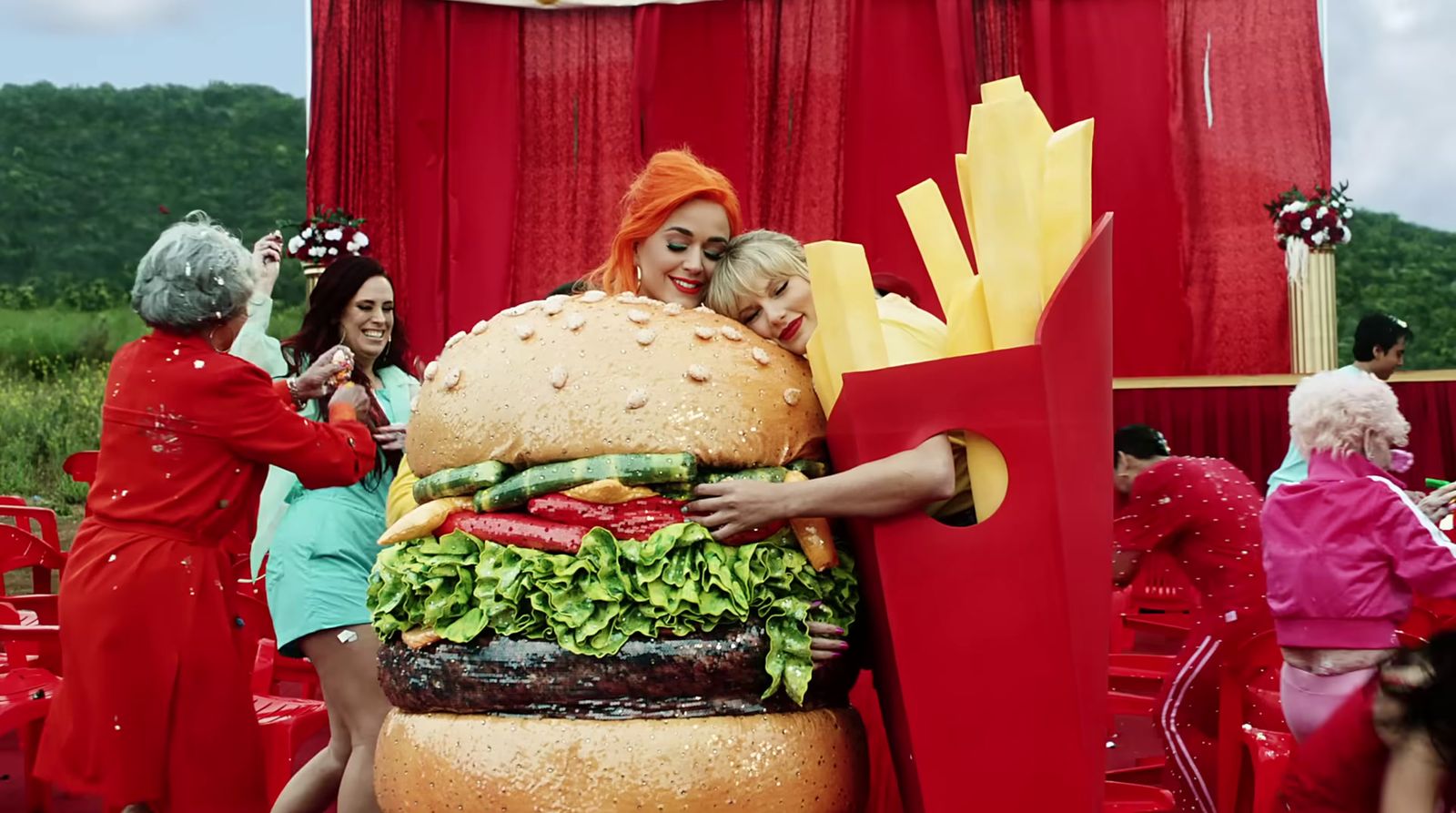 a woman holding a giant hamburger and french fries