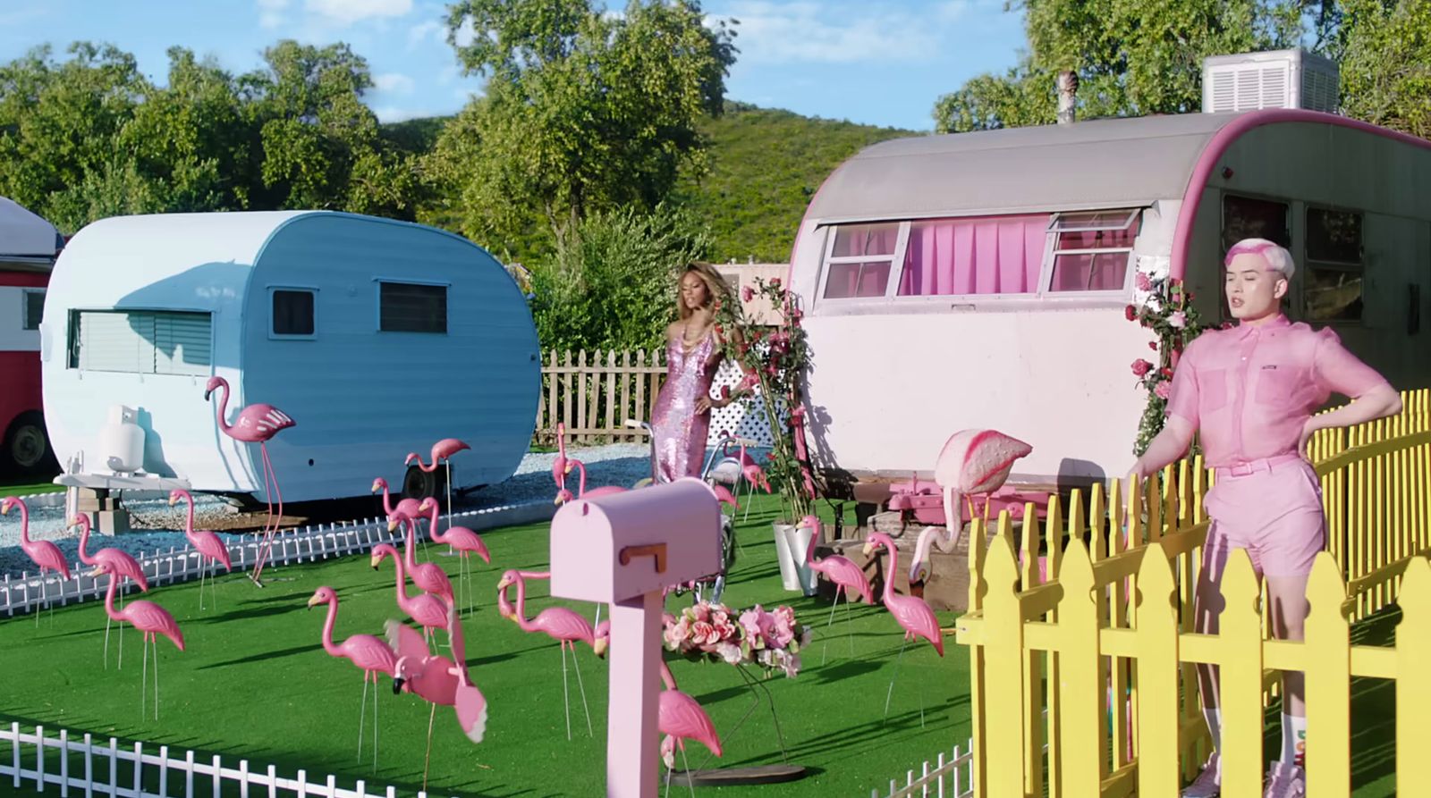 a group of pink flamingos standing in front of a trailer