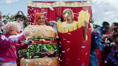 two women in costumes standing next to a giant hamburger