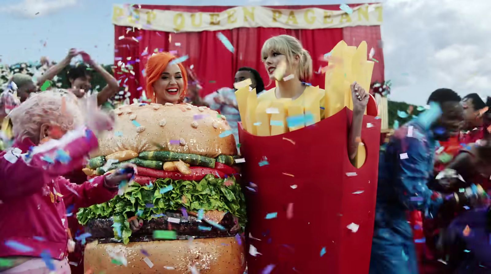 two women in costumes standing next to a giant hamburger