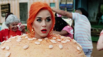 a woman with orange hair and makeup is standing in front of a group of people