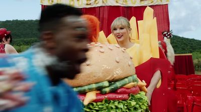 a woman standing in front of a giant hamburger