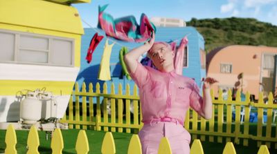 a woman in a pink outfit standing in front of a yellow fence