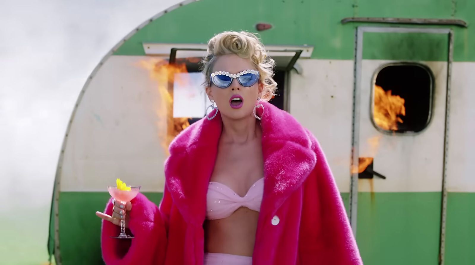 a woman in a pink coat and sunglasses holding a drink