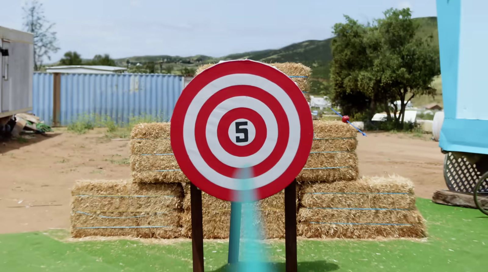 a red and white target sitting on top of a pile of hay