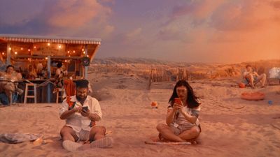 a group of people sitting on top of a sandy beach