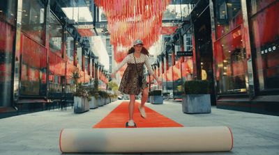 a woman walking down a red carpeted walkway