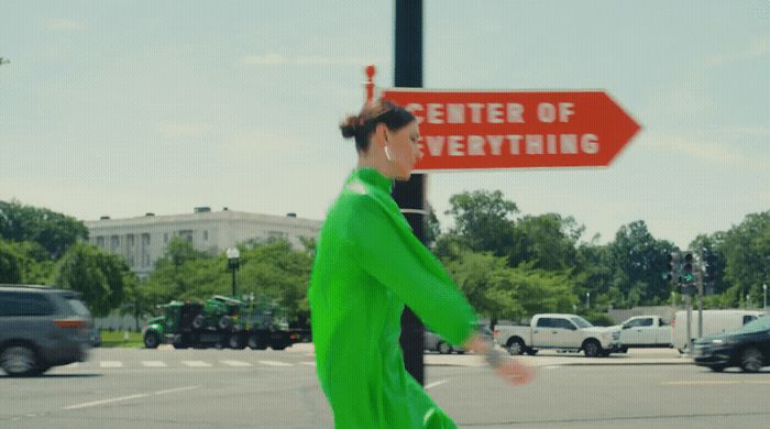 a woman in a green outfit crossing a street