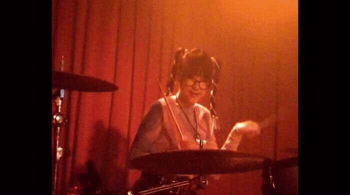 a woman playing drums in front of a microphone