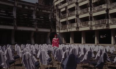 a woman in a red dress standing in a room full of chairs