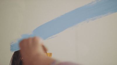 a woman is painting a wall with blue paint