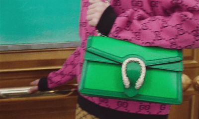 a woman holding a green purse with a ring on it