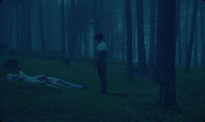 a man standing in the woods next to a dead body