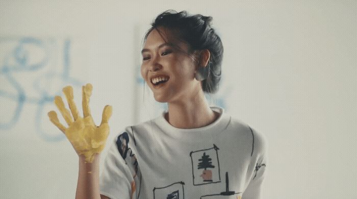 a woman holding up a pair of yellow gloves
