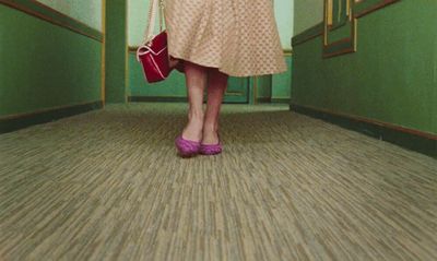 a woman in a pink dress is holding a red purse