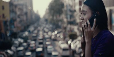 a woman talking on a cell phone next to a busy street