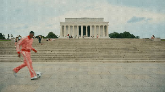 a man in a pink suit is kicking a soccer ball